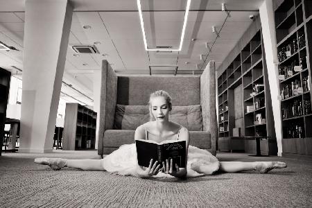 der Träumer. Ballerina auf Spitzenschuhen in der Bibliothek liest ein Buch und hält es hoch