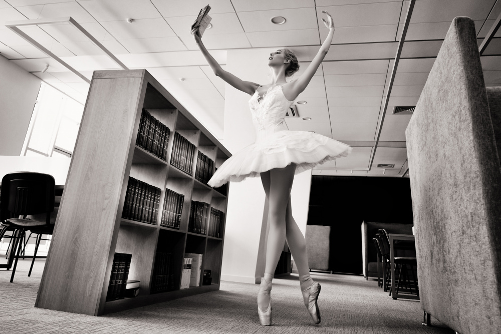der Träumer. Ballerina auf Spitzenschuhen in der Bibliothek liest ein Buch und hält es hoch from Alexandr