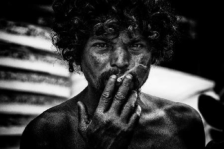 Ein Obdachloser,der in den Straßen von Delhi raucht.