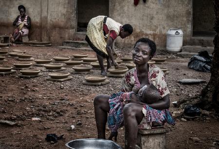 Eine Pause bei der Herstellung von Töpferwaren,um ihr Kind zu stillen – Ghana