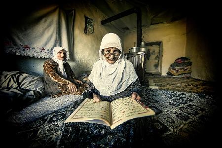Die alte Frau liest den Koran.