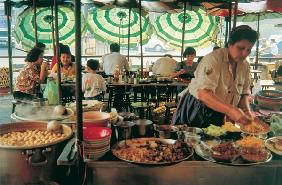 Cook preparing meals and sun-umbrellas hanging like large flowers in background (photo) 