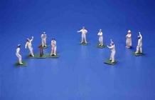 Eleven German bisque figures of cricketers and an umpire (painted lead)