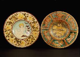 Two Della Robbia Wall Chargers, One Depicting A Putto Riding A Crescent Moon, The Other Designed By