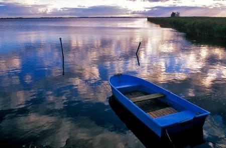 Blaues Boot am Seeufer mit Wolkenstimmung