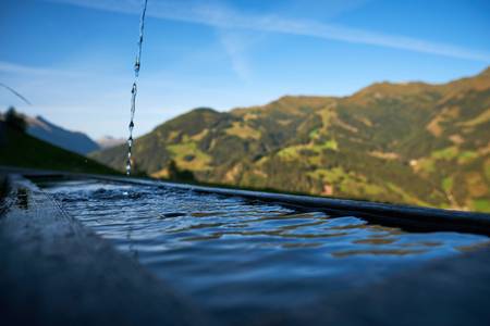 Holzbrunnen auf der Alm mit frischem sprudelndem Quellwasser